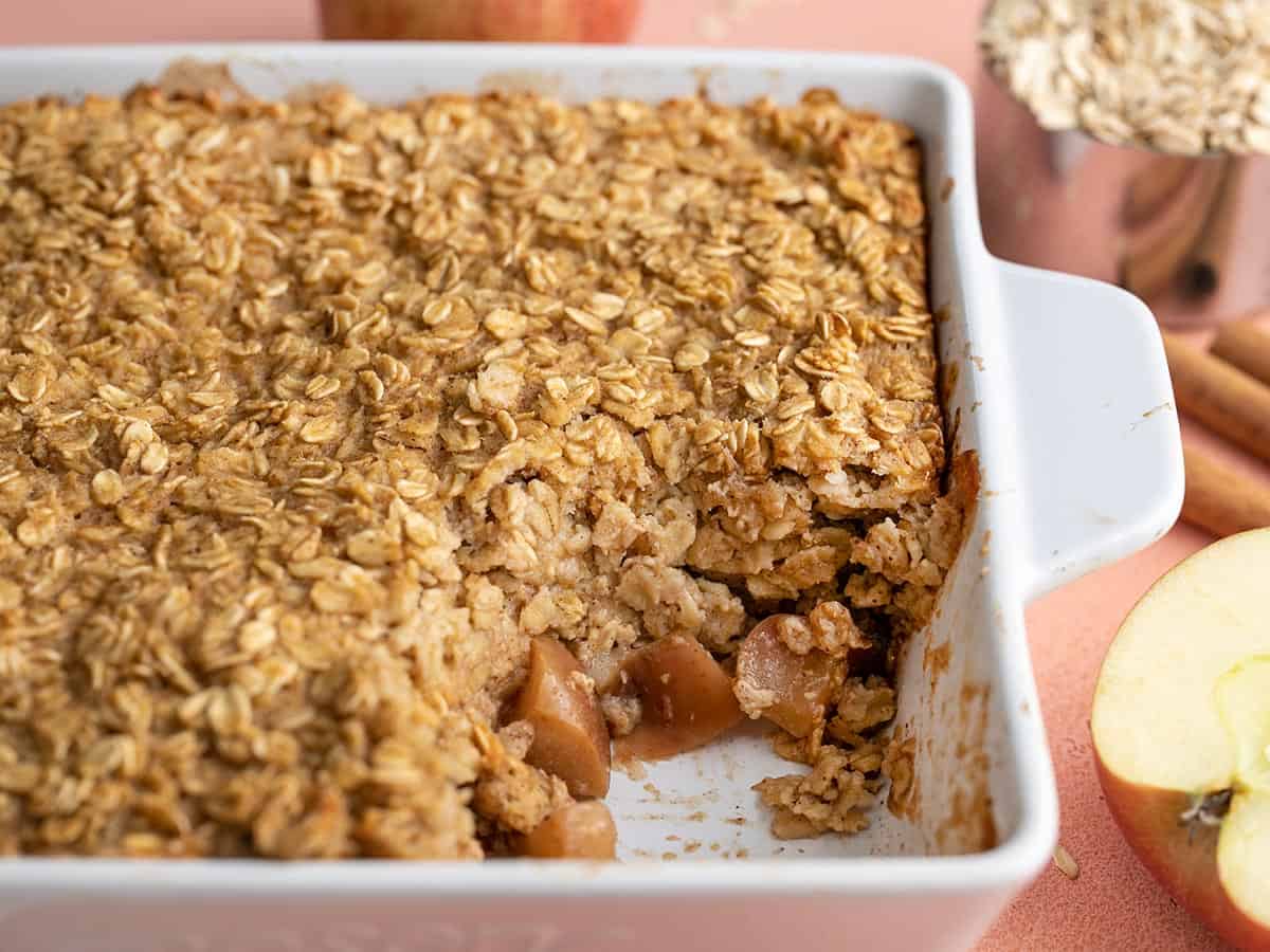 Side view of a casserole dish full of apple cinnamon baked oatmeal with a portion scooped out.