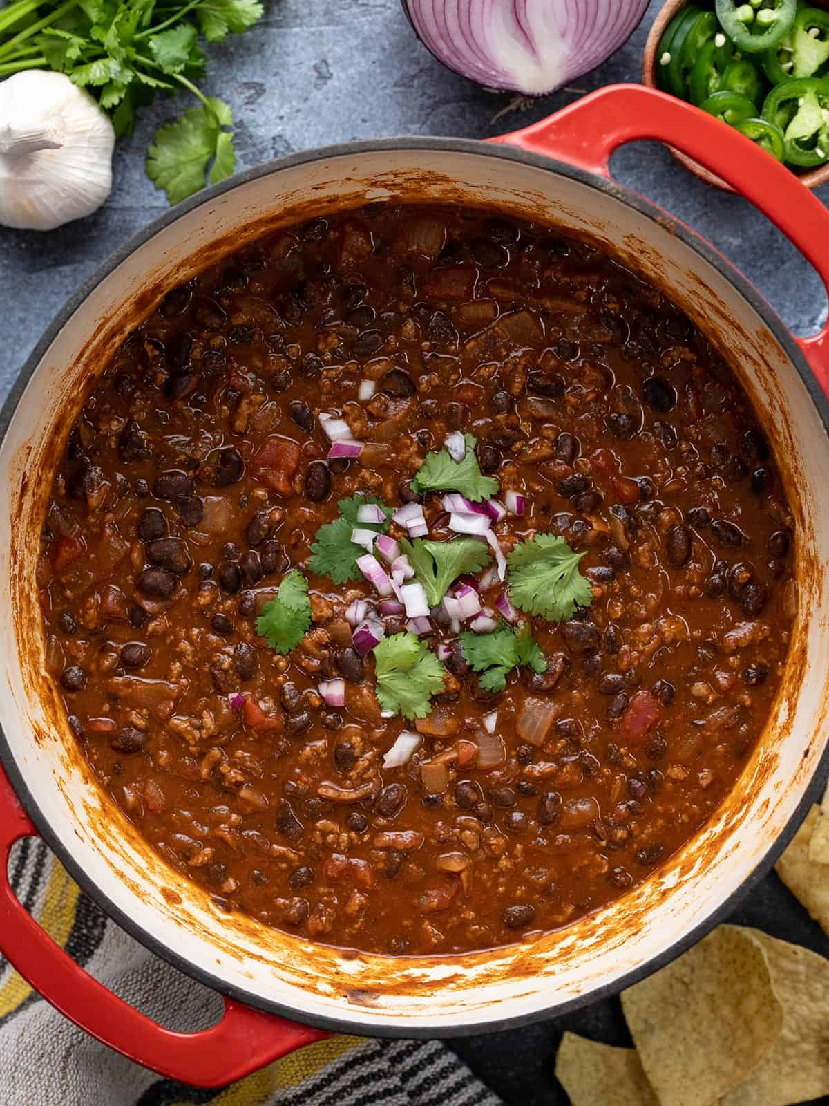 Overhead view of a pot full of black bean chili with toppings in the center of the pot.