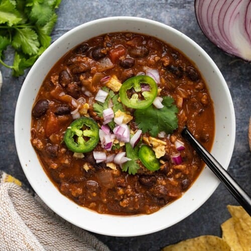 Overhead view of a bowl full of black bean chili with toppings.