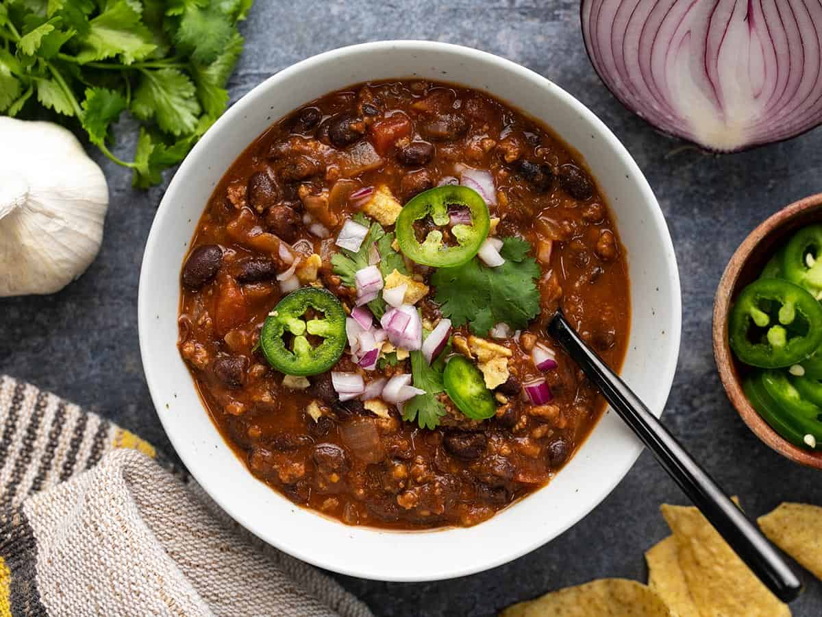 Overhead view of a bowl full of black bean chili with toppings. 