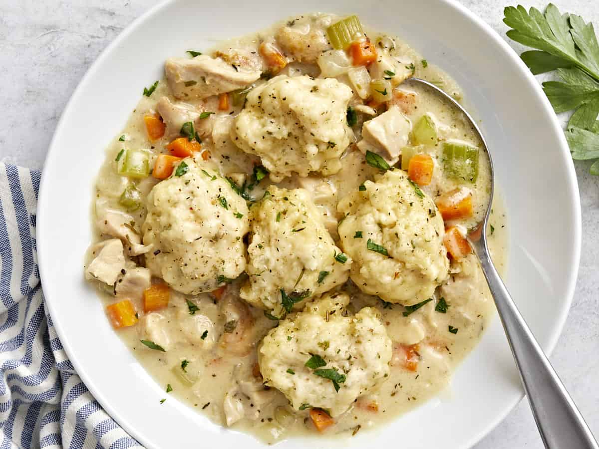 Overhead view of a bowl full of chicken and dumplings with a spoon in the side.