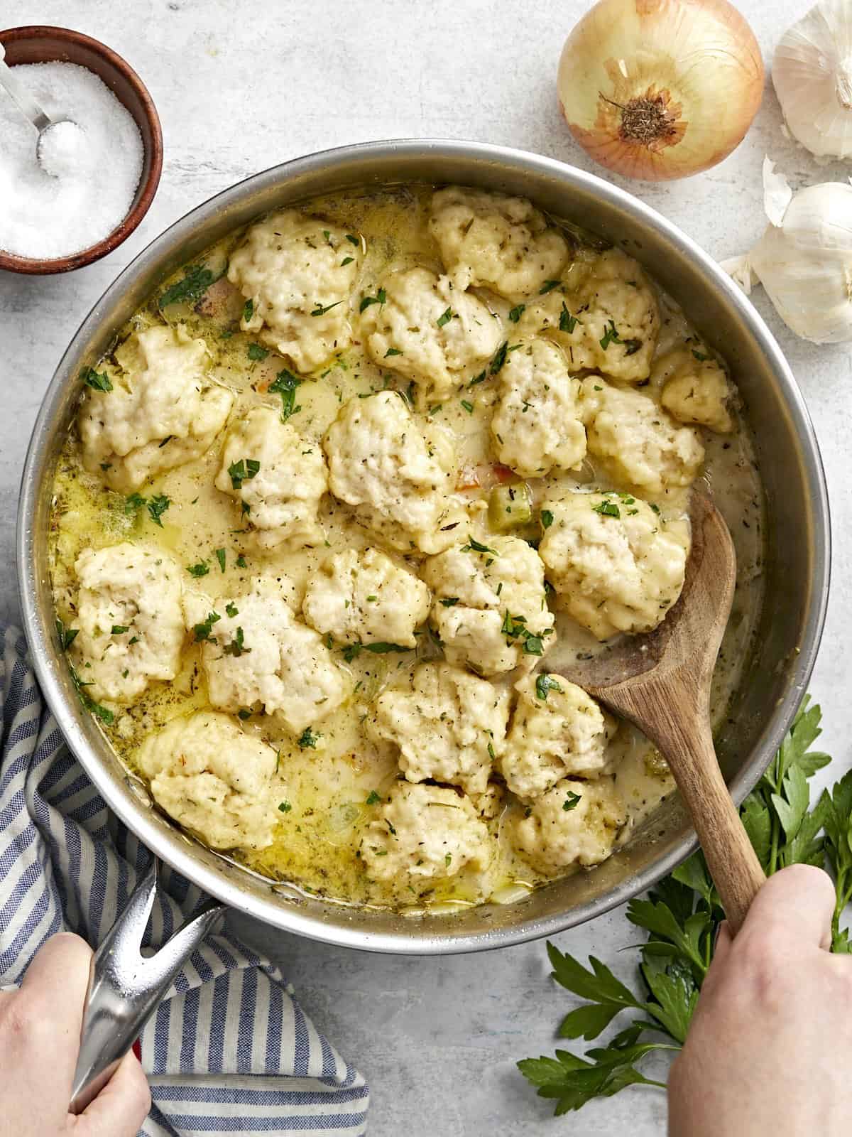 Overhead view of a skillet full of chicken and dumplings with a wooden spoon in the side.