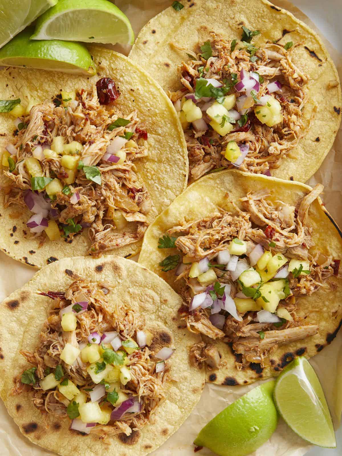Close up overhead view of four chipotle chicken tacos on a tray with pineapple salsa.