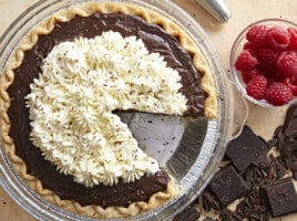 Overhead view of a chocolate cream pie with whipped cream on top and a slice removed.