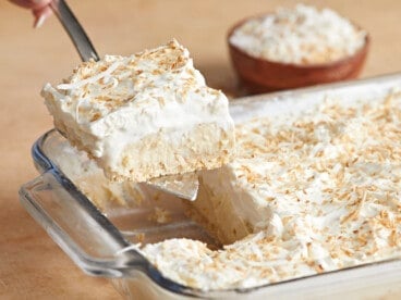 Side view of coconut cream pie bar being lifted out of the casserole dish.