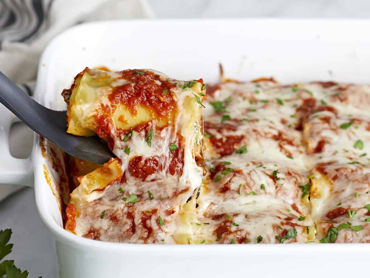 Side view of a lasagna roll up being lifted from the baking dish.