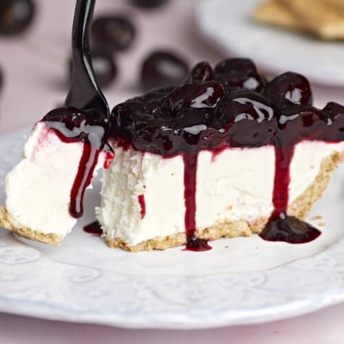 Side view of one slice of no bake cheesecake on a plate, a fork taking a bite.