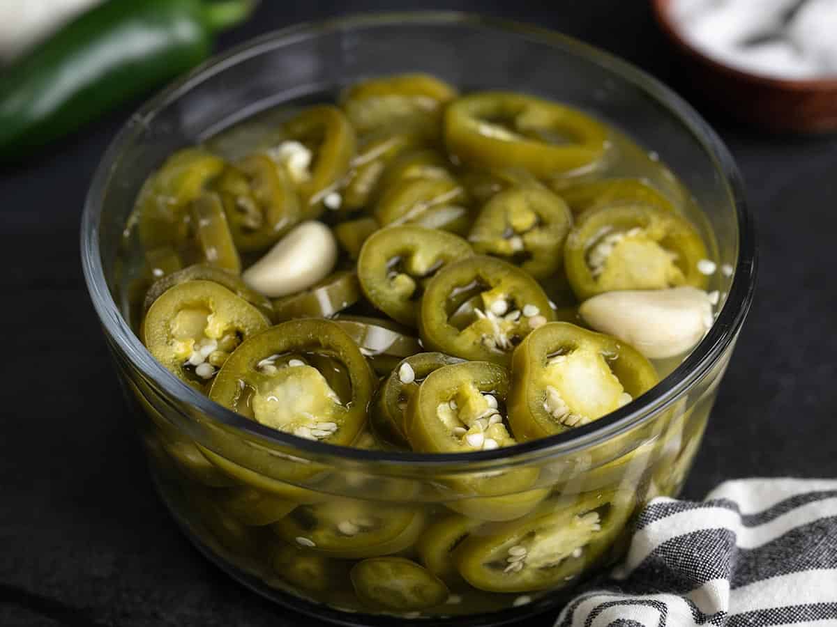 Side view of a bowl full of pickled jalapeños.