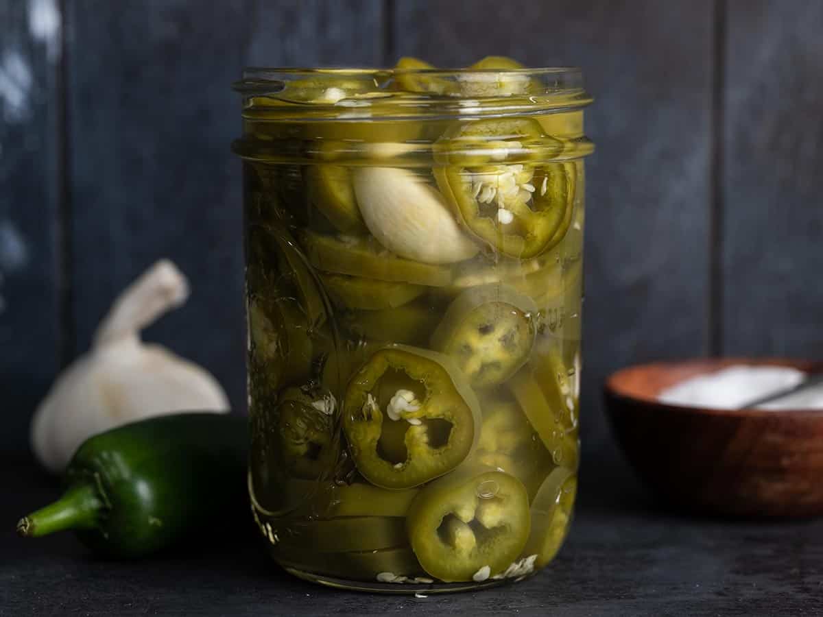 Side view of a jar full of pickled jalapeños.