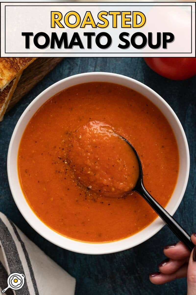 Overhead view of a bowl of roasted tomato soup with a spoon in the center.