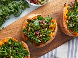 Three stuffed sweet potatoes on a wooden board.