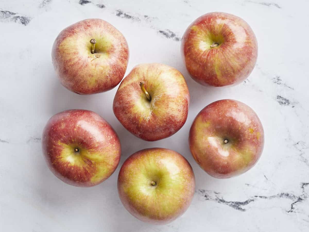 Overhead view of six apples on a counter.