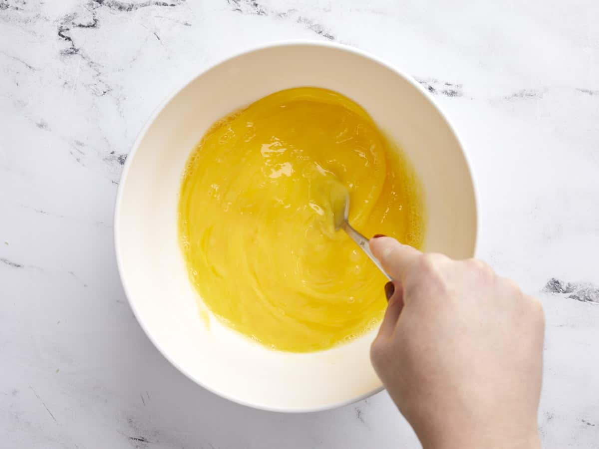 Eggs in a bowl being whisked with a fork. 