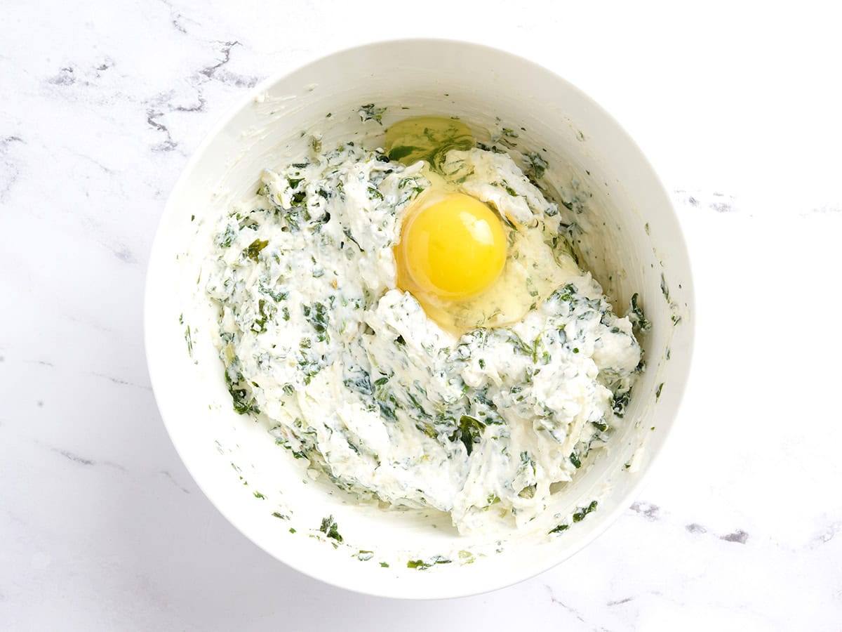 Spinach and ricotta in a bowl with an egg yolk.