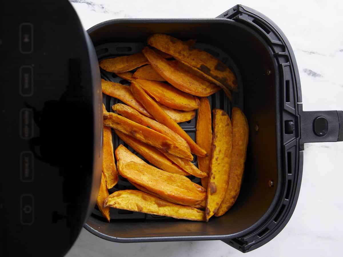 Cooked sweet potato fries inside air fryer basket.