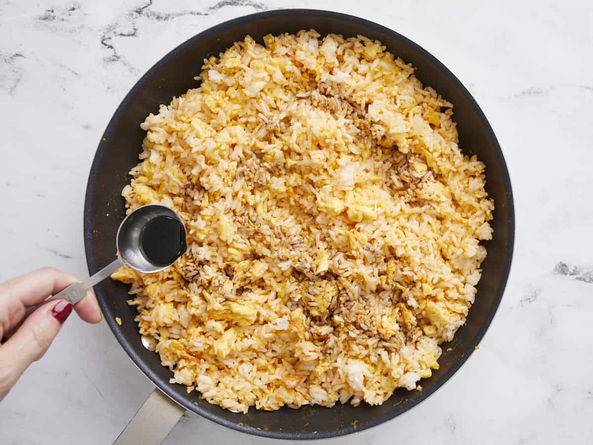 Rice and eggs being seasoned with soy sauce. 