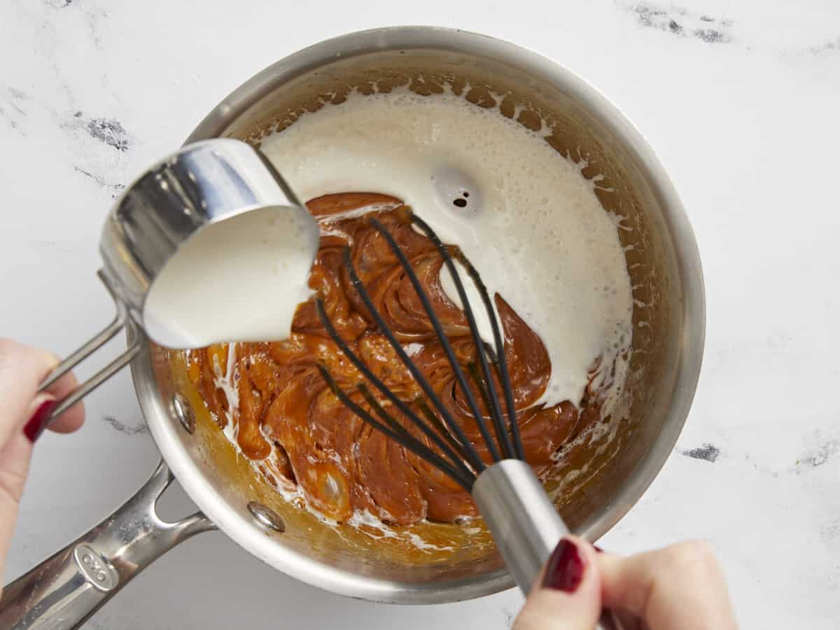 Heavy cream being poured into the caramel.
