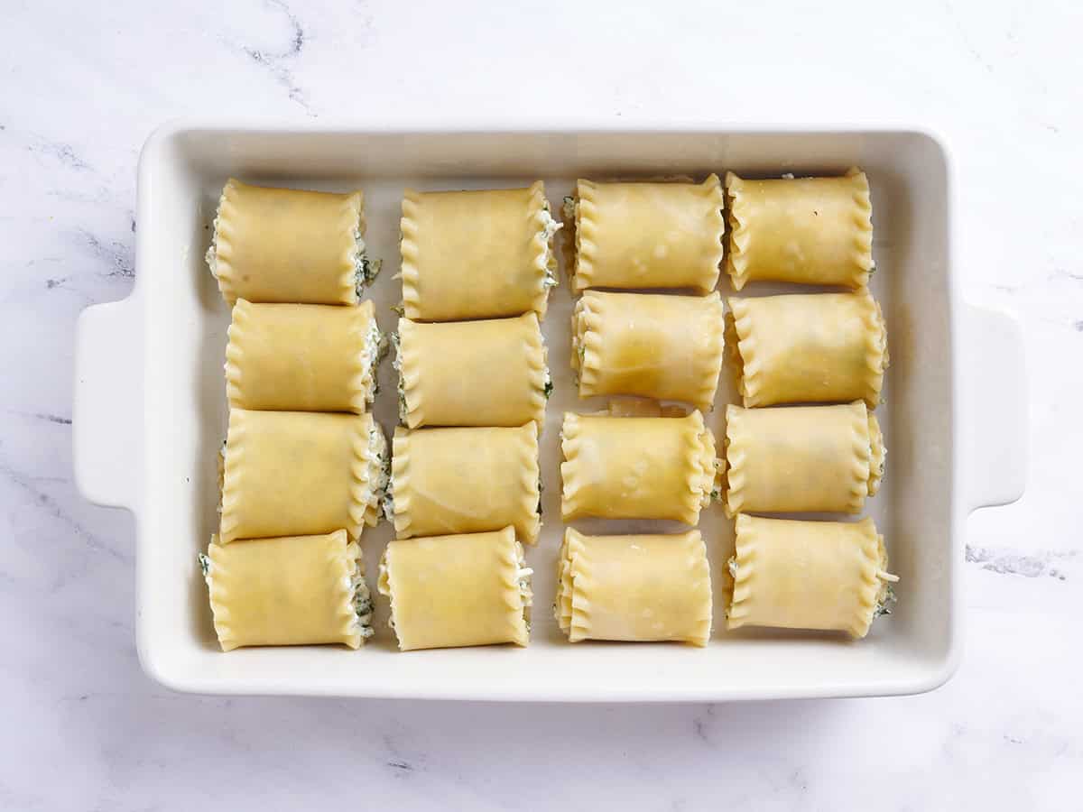 Spinach and ricotta lasagna roll ups added to a baking dish.