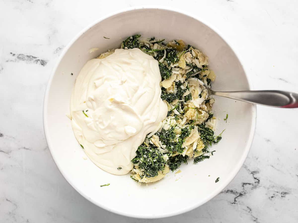 Creamy sauce added to bowl with spinach.
