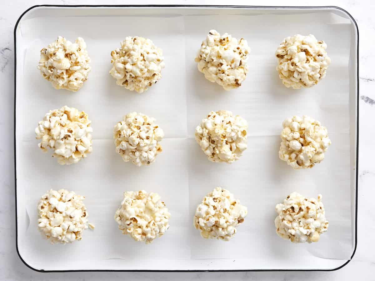 Overhead view of finished popcorn balls on a parchment lined baking sheet.