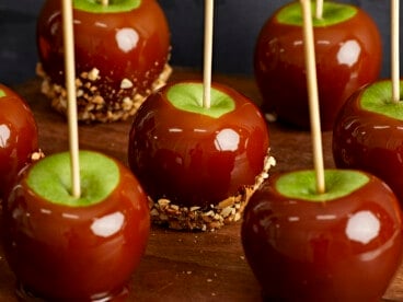 Caramel apples lined up in three rows, some with peanuts.