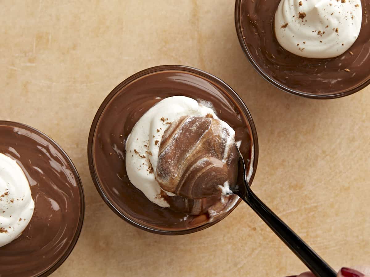 Top view of whipped cream being stirred into a cup of pudding.