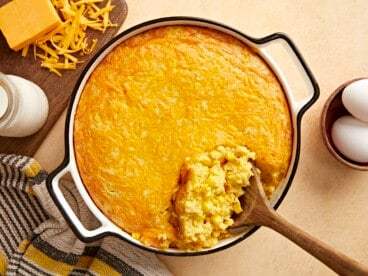 Overhead view of corn pudding being scooped out of the casserole dish.