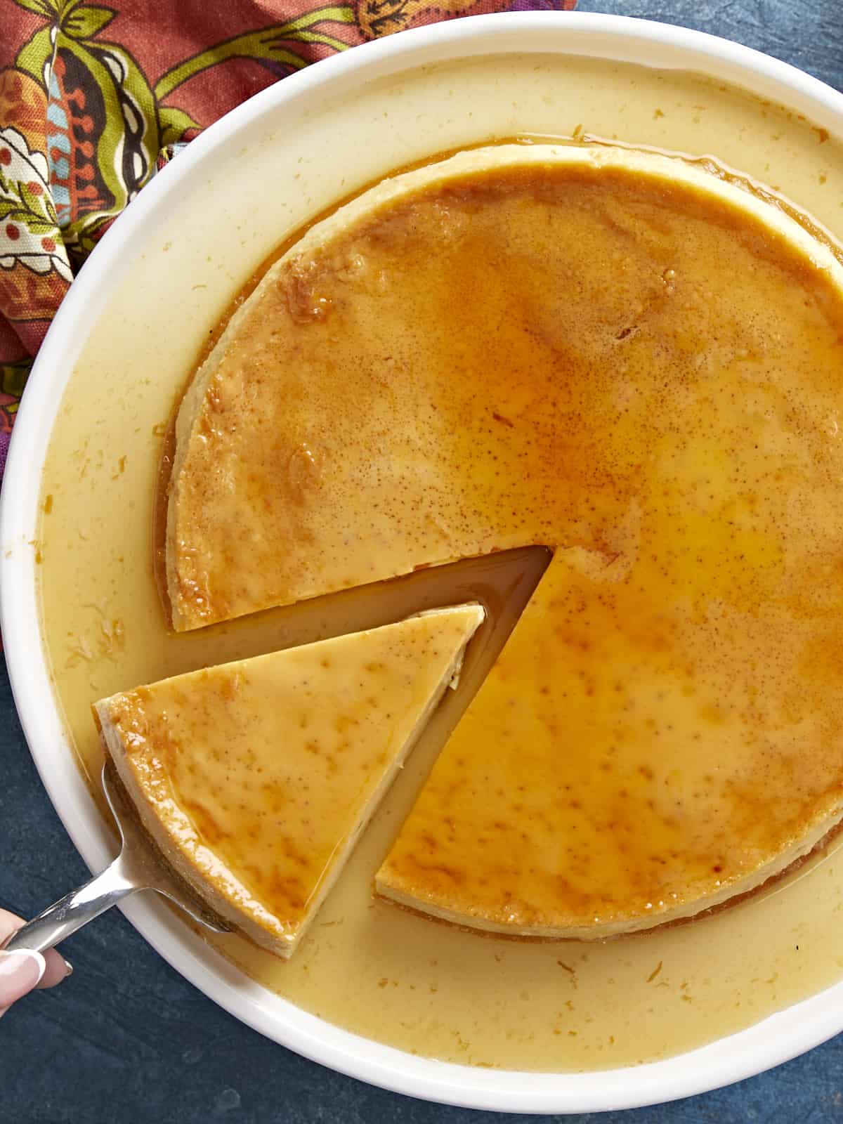 Overhead view of flan with one slice being lifted out.
