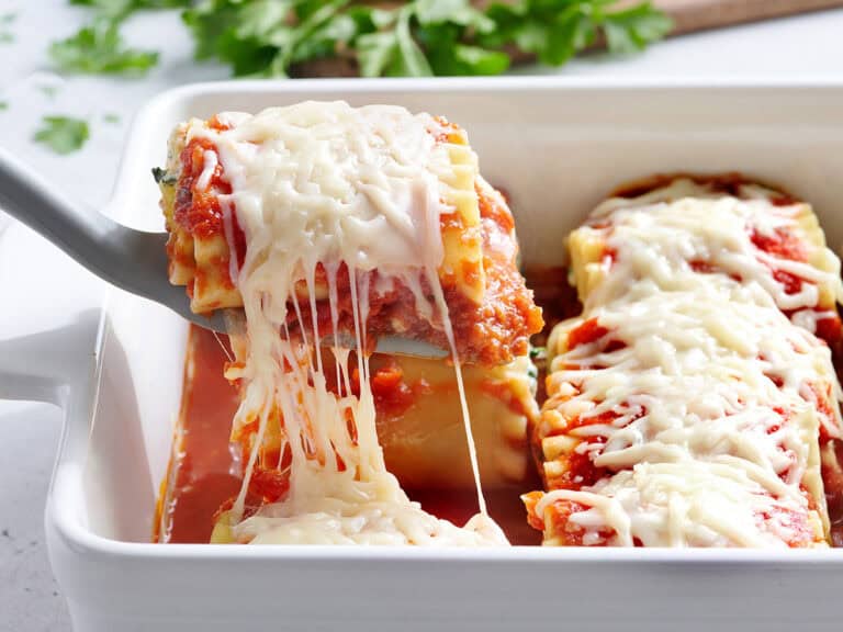 lasagna roll up pulled out of casserole dish on a spatula