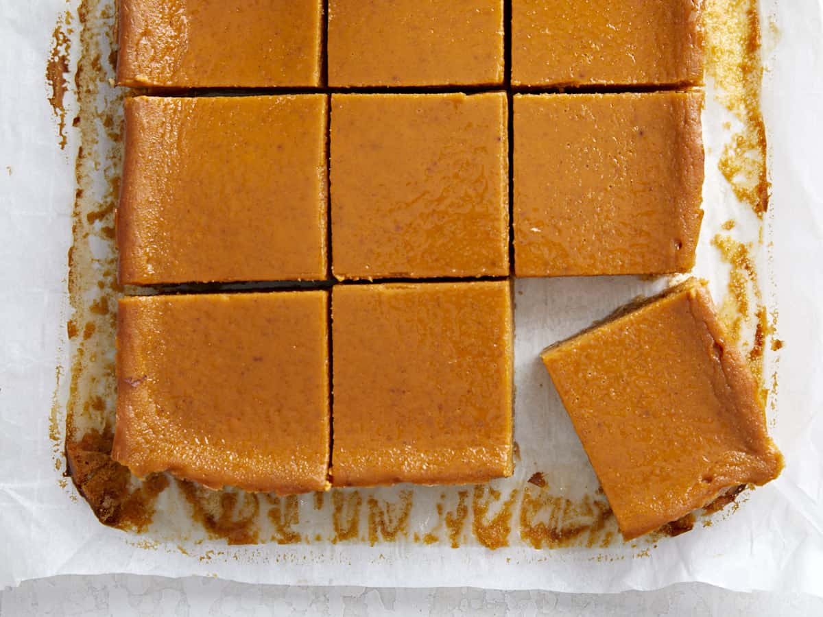 Overhead view of pumpkin pie bar squares on parchment paper.