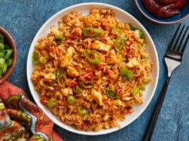 Overhead view of a plate full of scrambled eggs with rice, fork on the side.