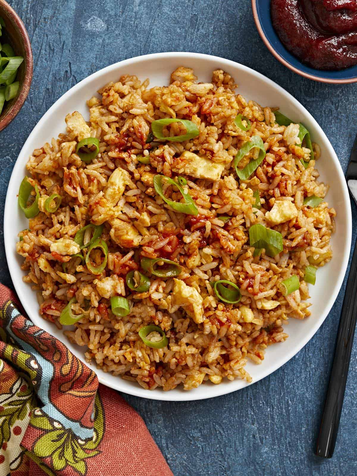 Overhead view of a plate full of scrambled eggs with rice, garnished with green onion.