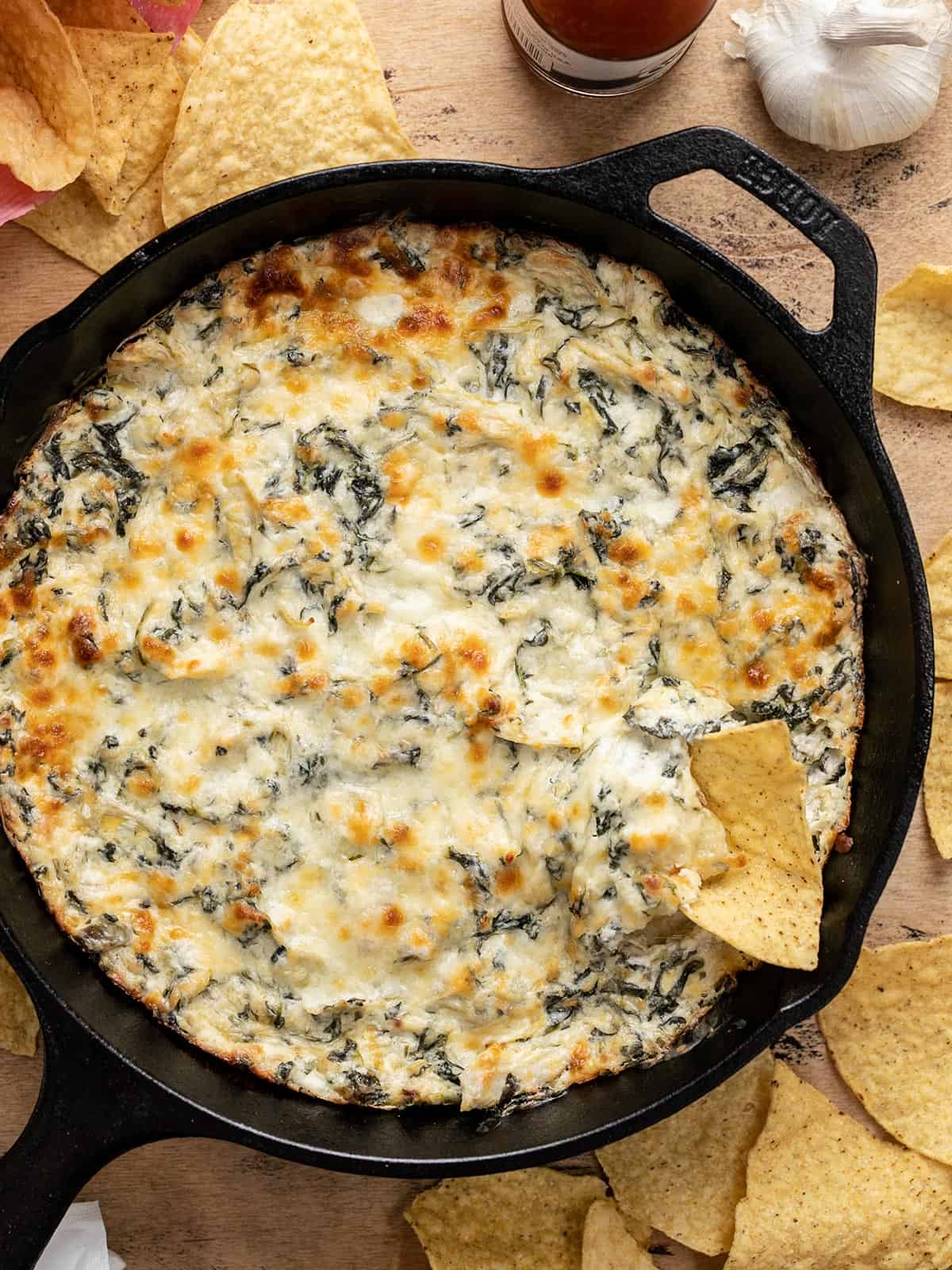 Spinach Artichoke Dip in a skillet with a chip dipping into the side.