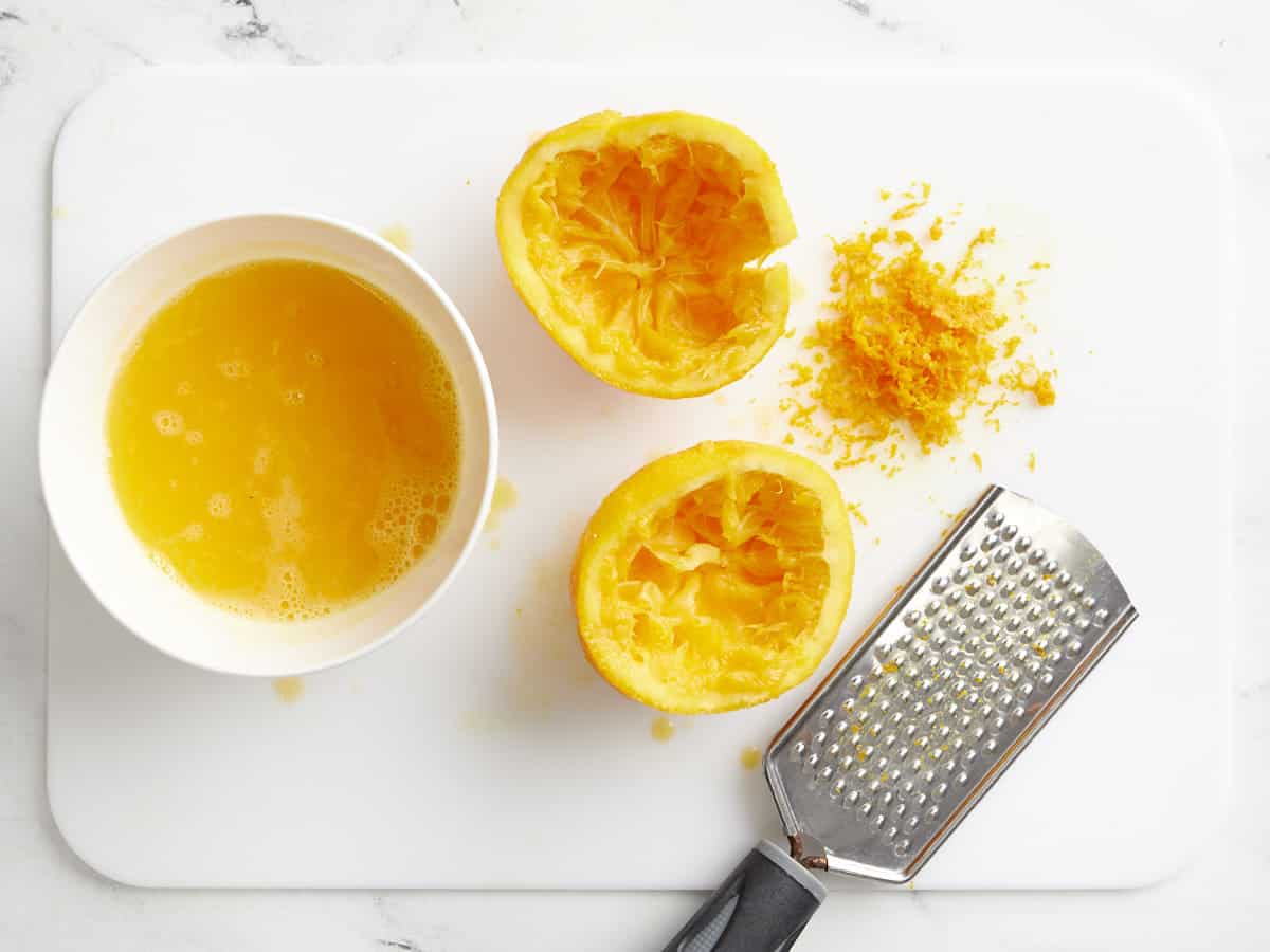 One orange zested and juiced on a cutting board. 