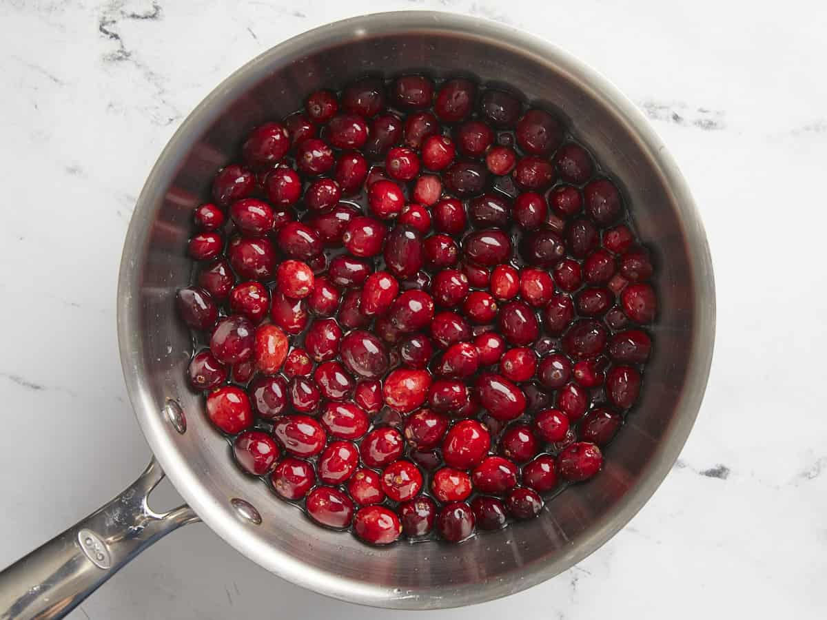 Fresh cranberries added to the pot with the water and sugar. 