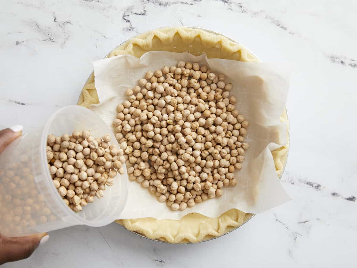 Overhead view of pie crust with parchment paper and pie weights on the inside.