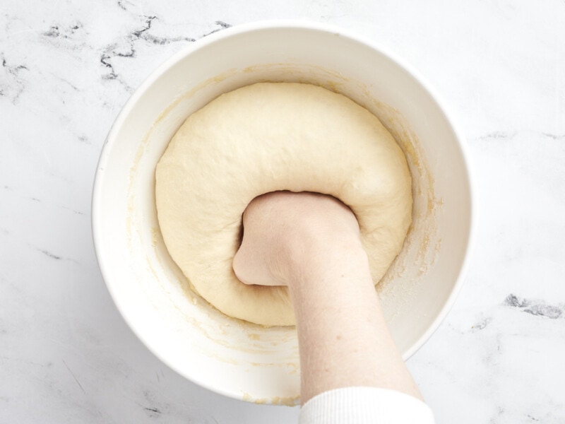 Punching down risen dough in the bowl.