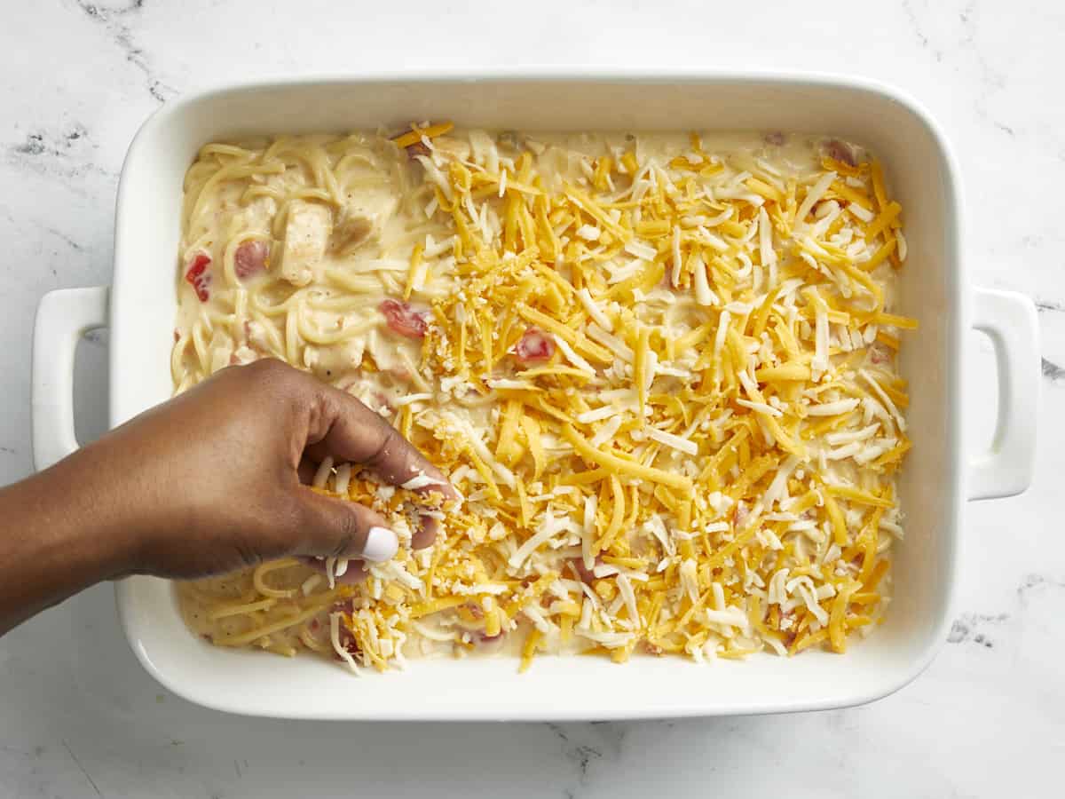Chicken spaghetti mixture added to a white baking dish with the remainder of the cheese sprinkled on top.