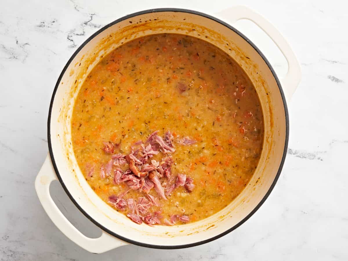 Overhead view of hamhock meat being added back to the pot.