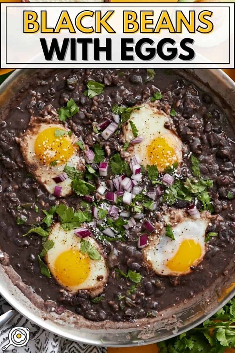 Overhead view of eggs poached in a skillet of black beans.