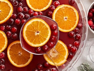 Close up overhead view of a punch bowl full of Christmas Punch with oranges and cranberries.