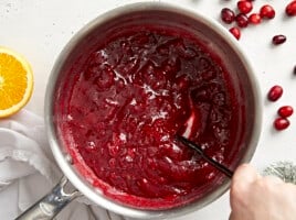 Thickened cranberry sauce in the pot being stirred.