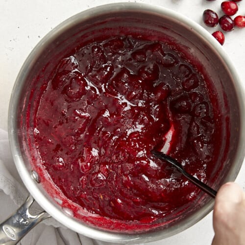Thickened cranberry sauce in the pot being stirred.