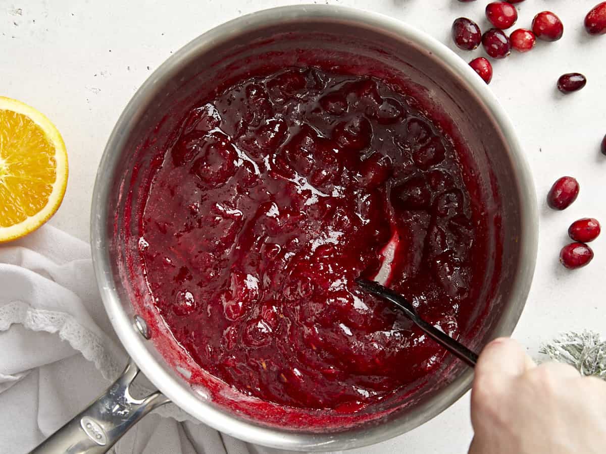 Thickened cranberry sauce in the pot being stirred. 