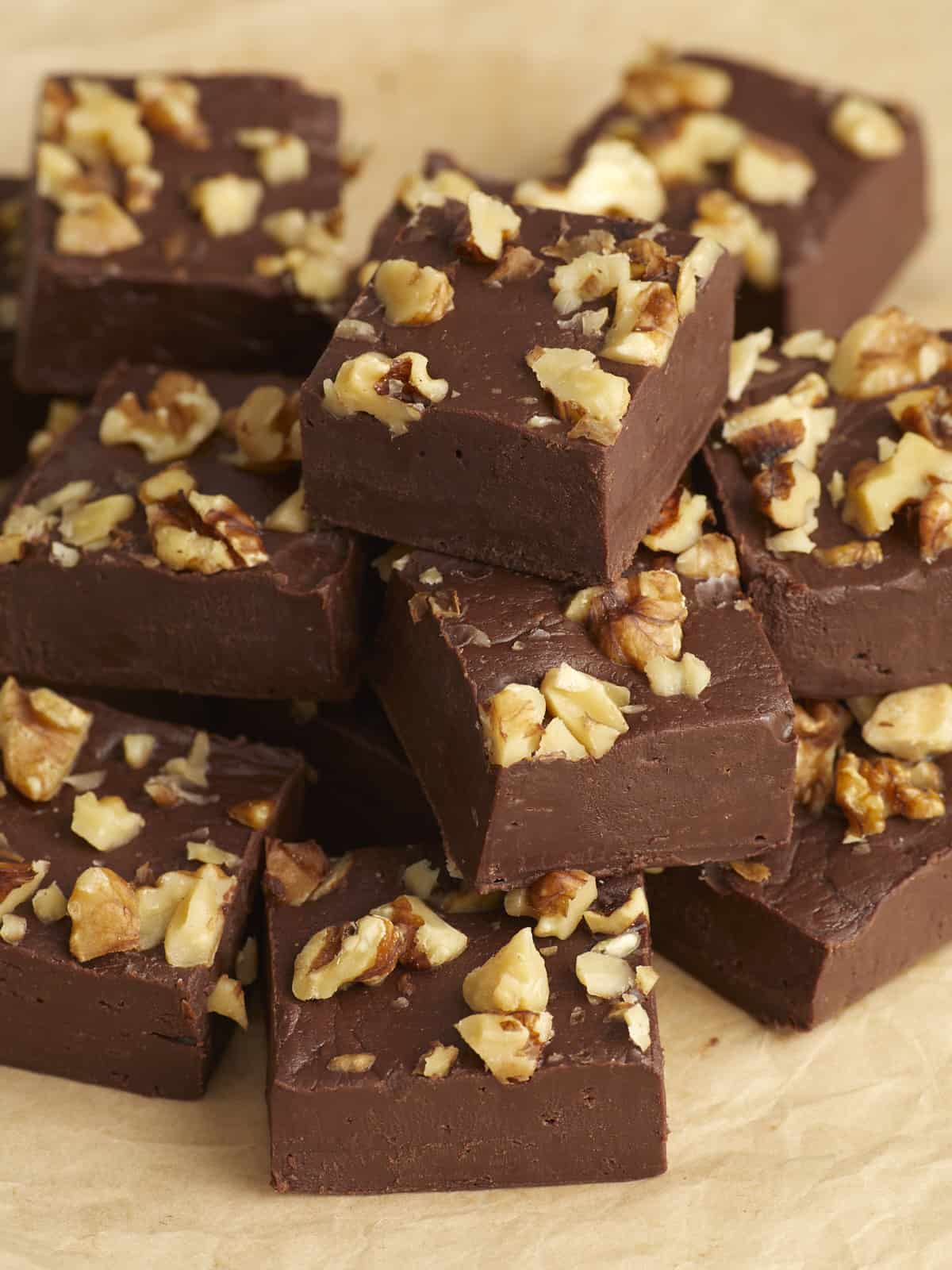 Side view of a pile of chocolate fudge squares with walnuts on top.