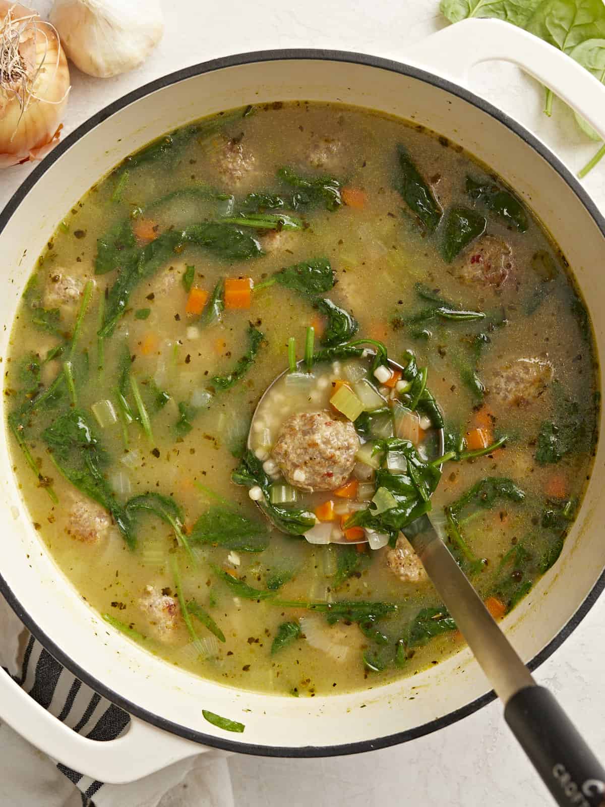 Overhead view of Italian Wedding Soup in the pot with a ladle.