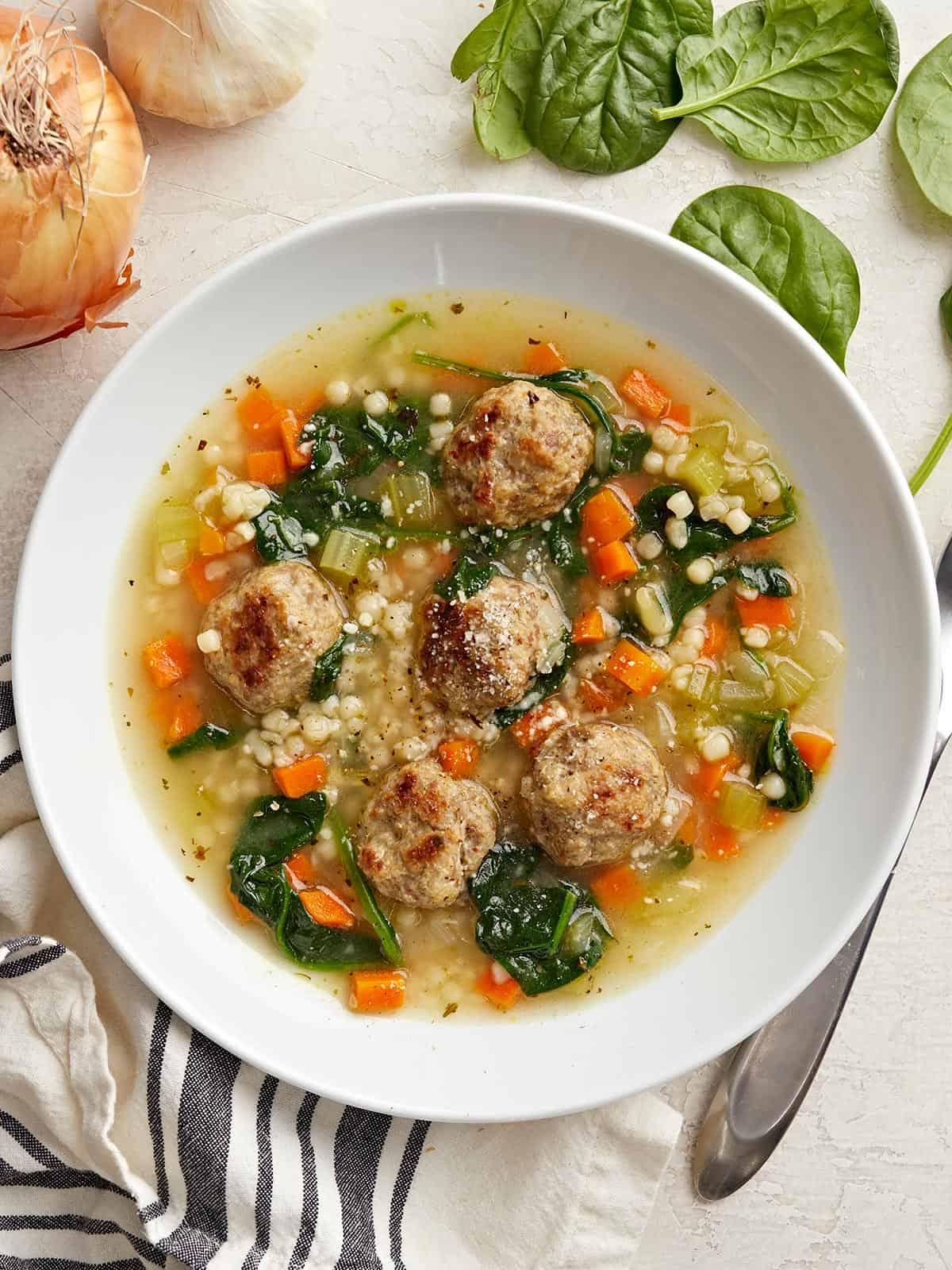 Overhead view of a bowl full of Italian Wedding Soup with bread on the side.
