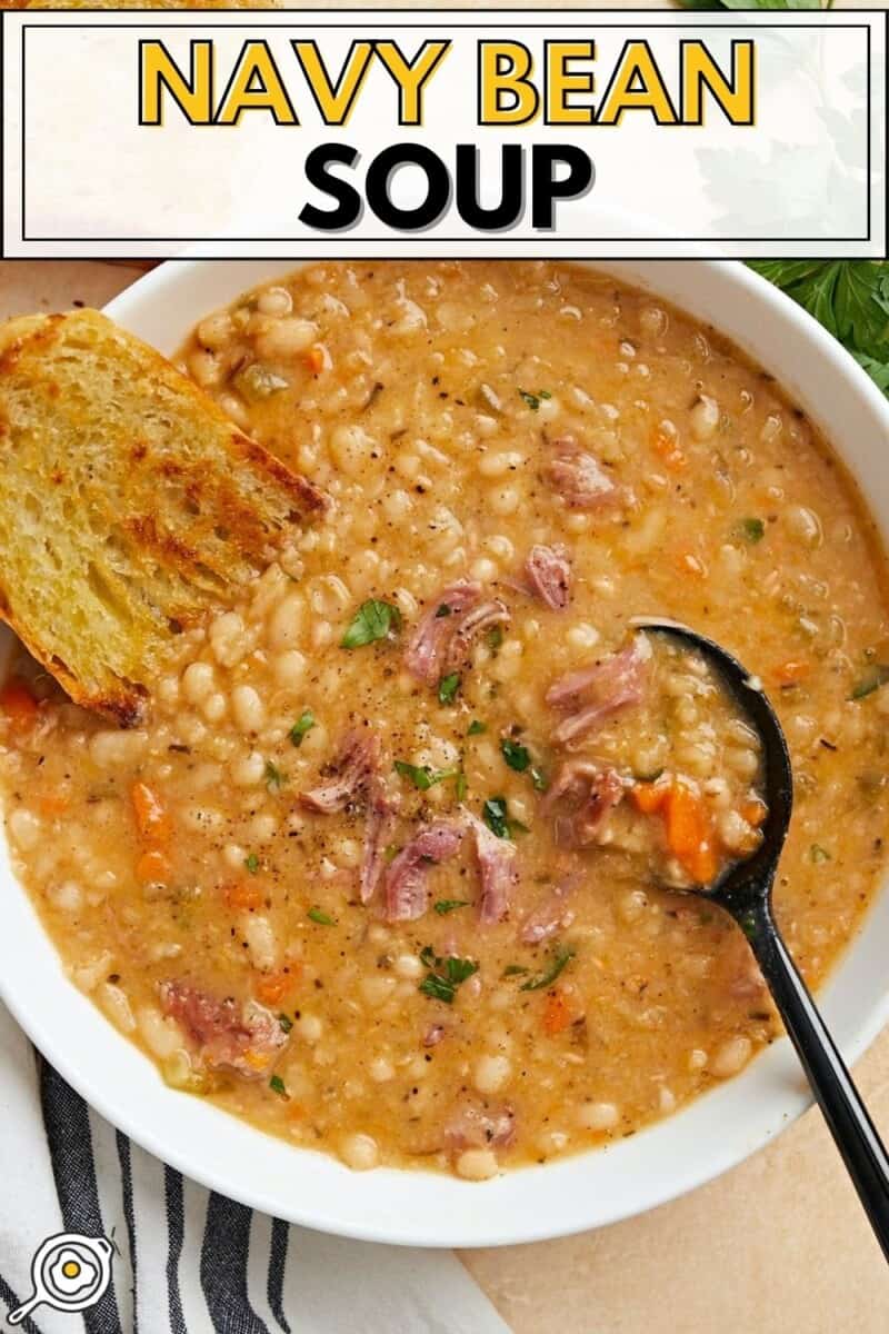 Overhead photo of a bowl full of navy bean soup with crusty bread and a black spoon on the side.