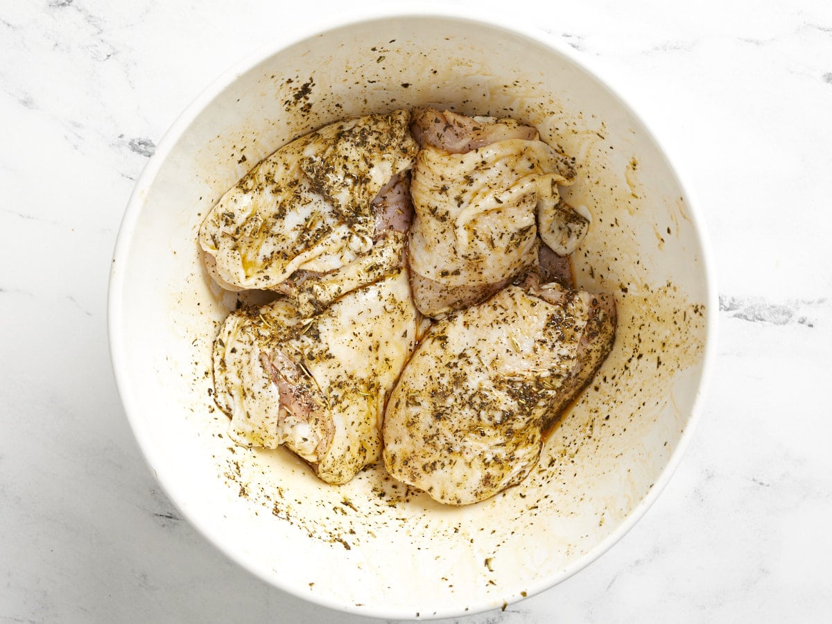 Seasoned chicken thighs in a bowl. 