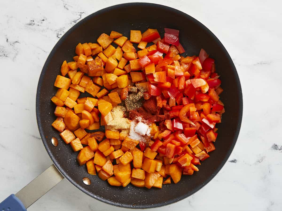 Sweet potatoes, bell peppers and spices added to skillet